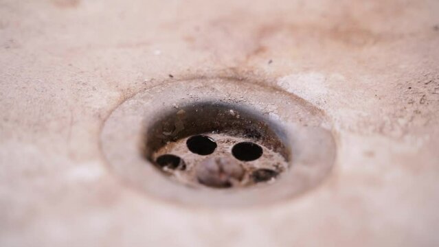 Dirty bathroom drain close-up. Plaque and dirt on the drain, smooth sliding of the camera