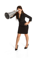 Young stylish girl, assistant and secretary looking through huge megaphone isolated over white background.