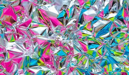 The surface of the crumpled foil is highlighted in different colors. Background holographic iridescent multicolored texture.