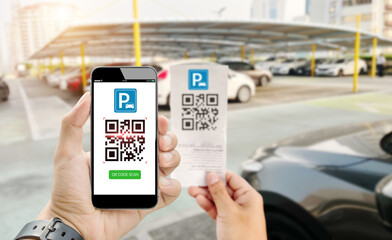 Qr code can parking payment concept.Hand holding mobile phone on blurred parking lot as background.