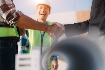 Construction workers, architects and engineers shake hands while working for teamwork and cooperation after completing an agreement in an office facility, successful cooperation concept.