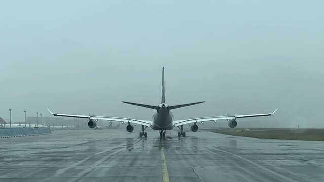 Rear view of an Airbus A340 taxing slowly on a taxiway during a snow shower. Pilot point of view.