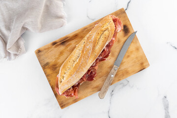 Spanish serrano ham sandwich on marble background. Top view
