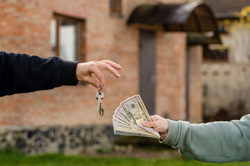 Exchange cash and key home in front of home. Buying or renting real estate. Mortgage. Insurance