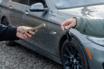 Deal of buying or renting car concept. Hand with car keys, other hand gives money.