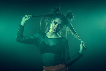 Portrait of beautiful cyber model woman posing at disco wearing orange leggings with neon glow fluorescent led light in a virtual tech blue environment