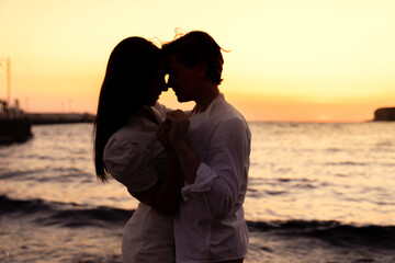 Photoshoot of young helthy beautiful couple, boy and girl, dating at the beach - Man and woman lovers dancing near the ocean in a sunny day looking at each others