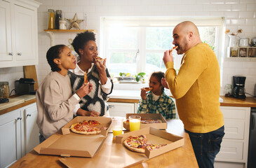 Family eating takeaway pizza at home and laughing