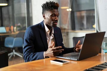 Portrait of successful businessman in office. Young smiling man using the laptop.