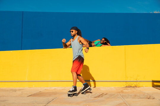 Black man on roller skates riding outside. Urban man posing with roller skates