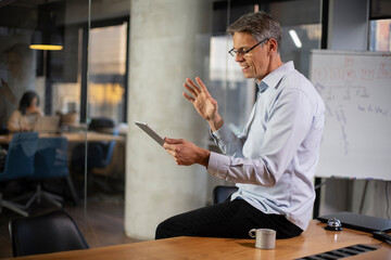 Fototapeta premium Portrait of businessman in office. Man using digital tablet. Businessman having video call.