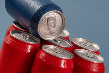 Cold red soda cans with a blue one for conceptual use