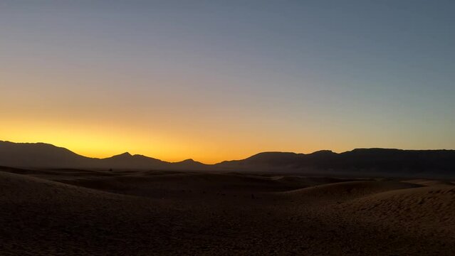 Beautiful scenic desert landscape with orange sunset behind mountains
