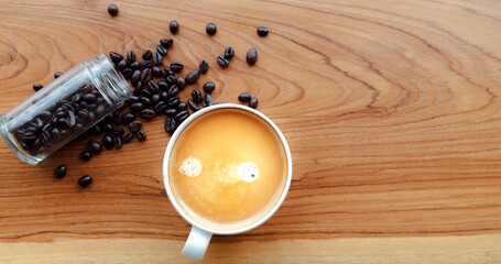 White cup of espresso coffee and Roasted coffee beans on a wooden background