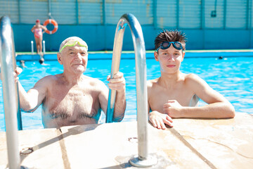 sports grandfather and grandson communicate in swimming pool