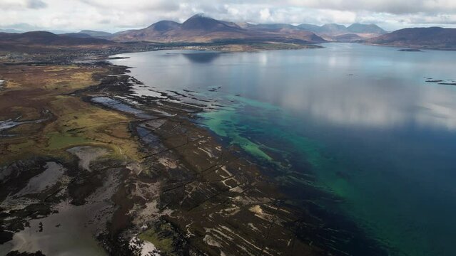 Beautiful reflection on the mountain landscape in the clear blue Broadford Bay at Isle of Skye. Drone tilt dolley shot