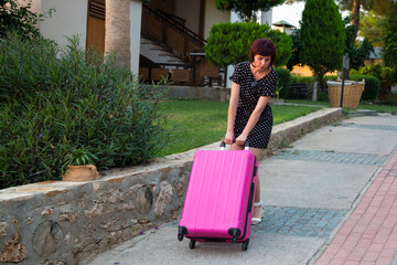 Woman with very heavy luggage, the concept of extra things on the way to vacation.