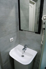 Toilet room interior with shower cabin, wash basin, hair dryer and mirror