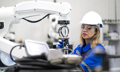Robotic maintenance engineer working on robot arm connection equipment. Smart women learning training industry 4.0 intelligence robotic engineering at futuristic electronic technology academy workshop