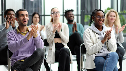 Selective focus of young businesswoman applauding together with interracial colleagues during seminar