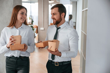 Front view. Man and woman are with eco boxes that is with food is in the office together