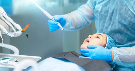 Male dentist with female patient in dental chair providing oral cavity treatment. - obrazy, fototapety, plakaty