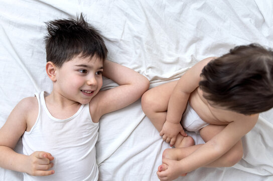 emotional photo with two brothers lying on bed hugging kiss each other cuddling and caresses.big brother kissing little one.different face expression emotion kids child baby boy maternity concept top 
