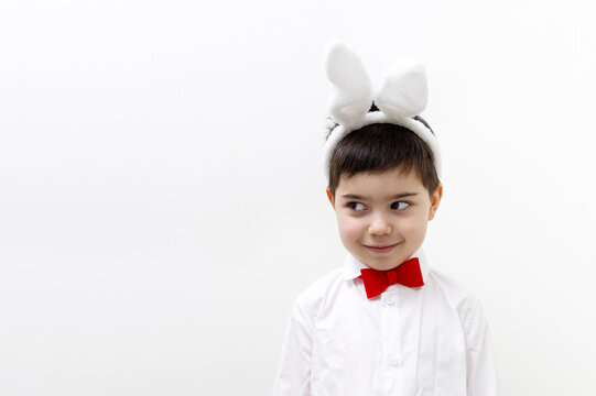 pre schooler boy with bunny rabbit ears headband and red bow at neck isolated pointing with finger up wow amazed shocked expression.child kid in baby crib or at table desk using laptop smiling easter