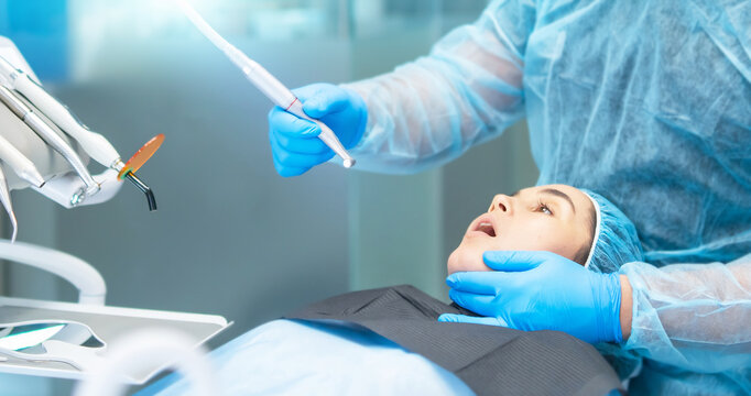 Male dentist with female patient in dental chair providing oral cavity treatment.