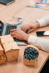 Typing on keybord. Top view of hands of the man that is working by using laptop. Eco boxes with food and blueberries