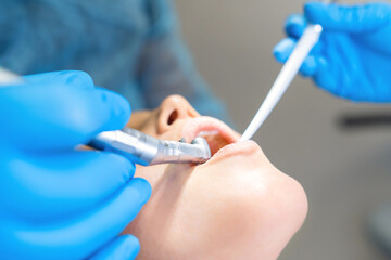 Closeup photo of male dentist with female patient in dental chair providing oral cavity treatment.