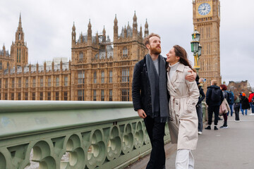 Fototapeta na wymiar Happy couple of young travelers walking on Westminster Bridge with Bin Ben in the background