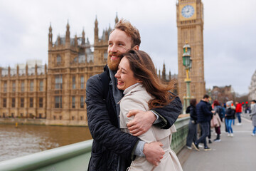Happy couple of young travelers embrace against the background of London's Big Ben