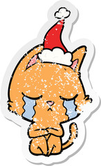 crying distressed sticker cartoon of a cat sitting wearing santa hat