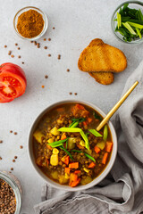 Healthy vegetarian lunches, brown lentil soup with tomatoes and carrots, green onions, potatoes and curry spices, toasted croutons, top view