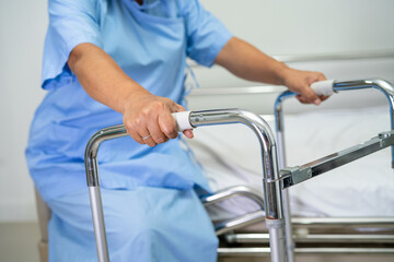 Asian lady patient use walker in hospital to support walking.