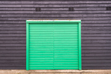 Wooden green door on a black barn building.