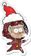 happy astronaut distressed sticker cartoon of a wearing santa hat