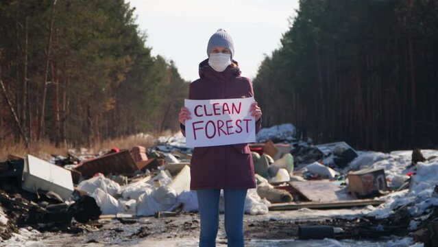 A woman in a landfill with a "Clean Forest" placard.
Ecological problems and pollution of nature.