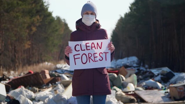 A woman in a landfill with a "Clean Forest" placard.
Ecological problems and pollution of nature.