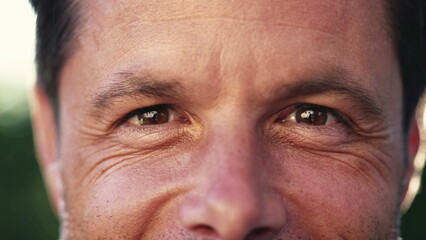 Macro eyes of a happy man looking at camera. Close up of male 40s middle aged person smiling with wrinkles. Person eyesight vision closeup