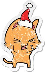 distressed sticker cartoon of a cat hissing wearing santa hat