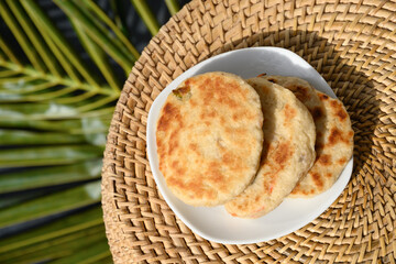 Amazing Sri Lankan three Pol Coconut Roti in white plate. Traditional flat bread with red onion and...