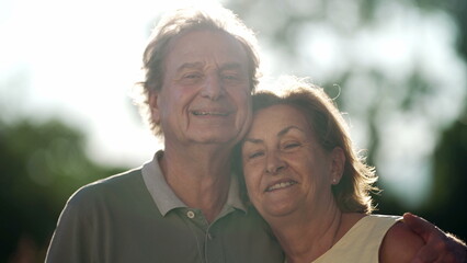 Happy senior couple posing for camera standing in nature. Older husband embracing wife smiling. 70s people