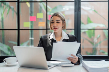 Fototapeta na wymiar Young business woman, or company employee holding accounting bookkeeping documents checking financial data or marketing report working in office with laptop. Paperwork management
