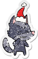 friendly distressed sticker cartoon of a wolf wearing santa hat