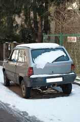 Obraz na płótnie Canvas Gdynia, Poland - 03 10 2023: Tiny retro car abandoned on the street close-up during snowy weather.