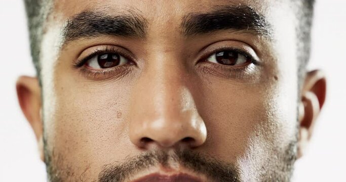 Closeup, face and serious man in studio for skincare, confident and stare against white background. Zoom, young and portrait of Indian male model with wellness, beauty or cosmetic routine isolated