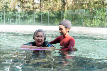 Young trainer helping senior woman in aqua aerobics and working out in the pool. old woman and...