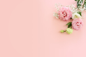 Top view image of delicate pink lisianthus flowers over pastel background